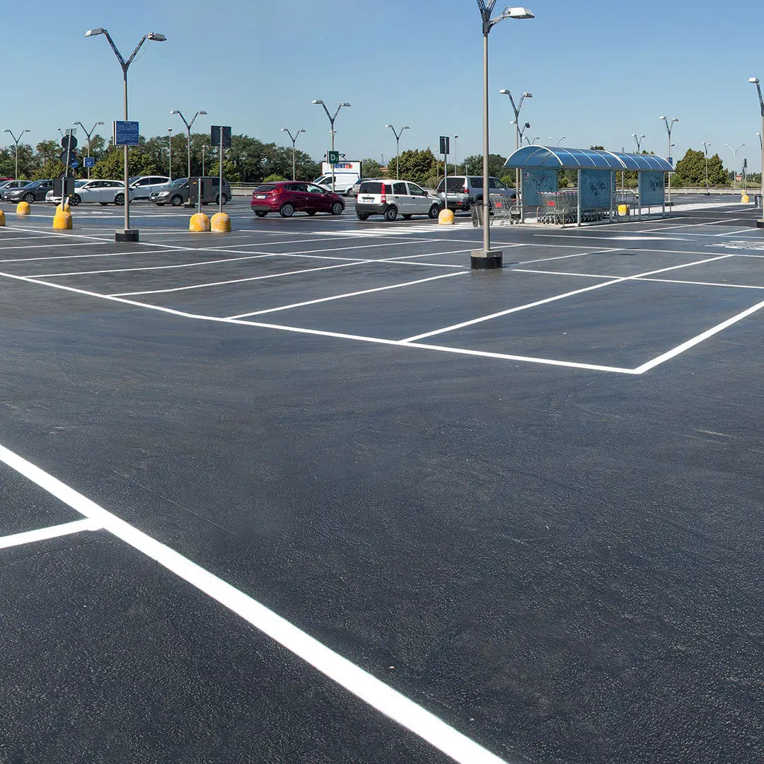 Freshly coated car park surface with clear white line markings, showcasing a durable epoxy or resin flooring system under bright daylight