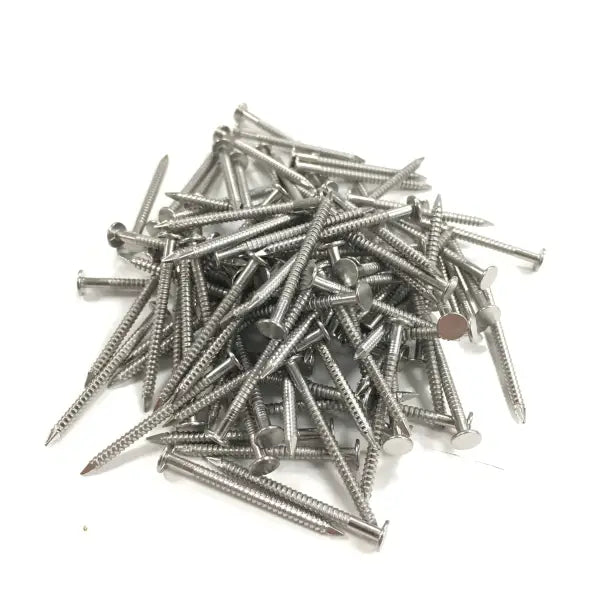 Pile of silver stainless steel fixing pins scattered randomly on a surface