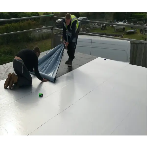 Construction workers installing Eagle GR100 VCL metal roofing material on a building