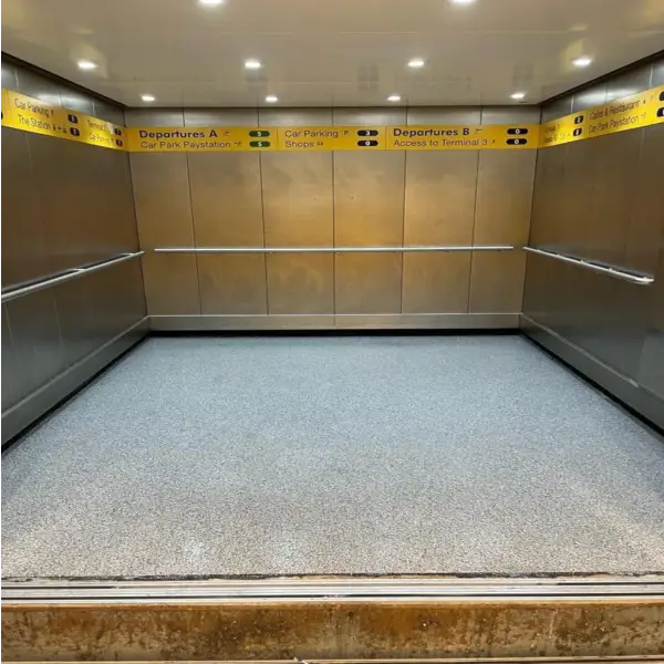 Empty elevator interior featuring stainless steel walls and handrails by EleDeck Polyaspartic