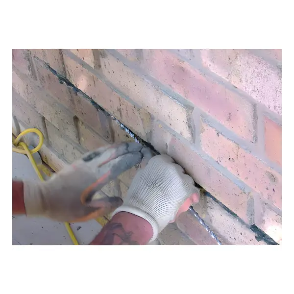 Gloved hands applying Helical Remedial W60 Flexi-Grout mortar between bricks