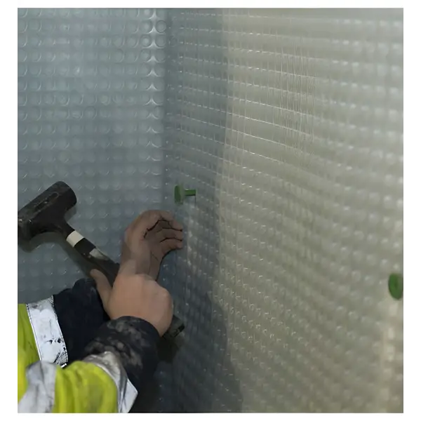 Hands holding a hammer installing Surefix Green CM Brick Plugs on a textured wall