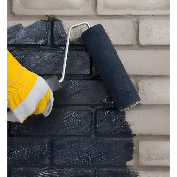 Paint roller applying black paint to a brick wall with Technoseal DPM Damp Proofing Membrane