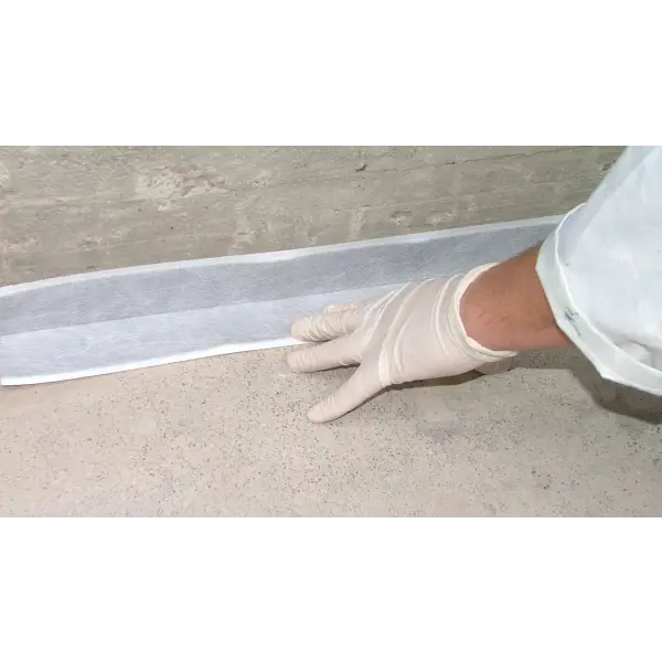 Gloved hand applying Winkler ONE BC Seal Band tape on a floor surface