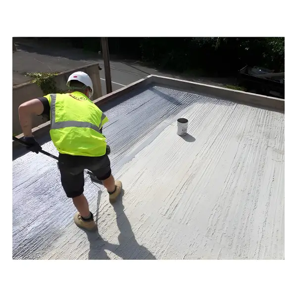 Worker in high-visibility vest applying reflective coating on flat roof with Wykamol EP40