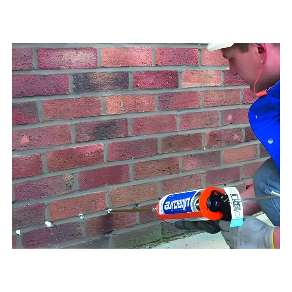 Caulking gun using Wykamol No More Damp sealant on brick wall holes for repairs